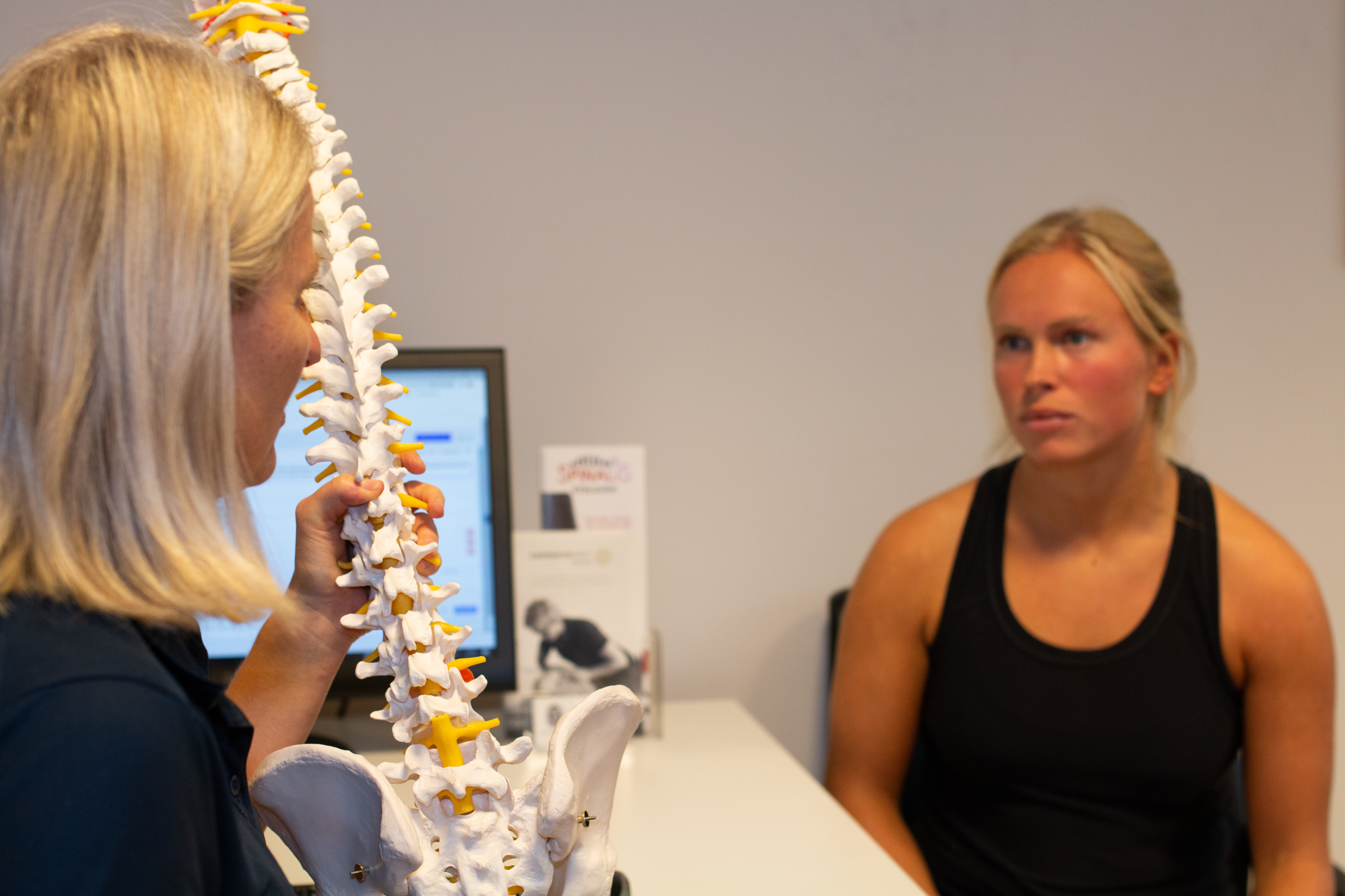 Individuell veiledning i behandling. Fysioterapeut forklarer ryggradsmodell. Vi hjelper deg å forstå årsaken til smertene.