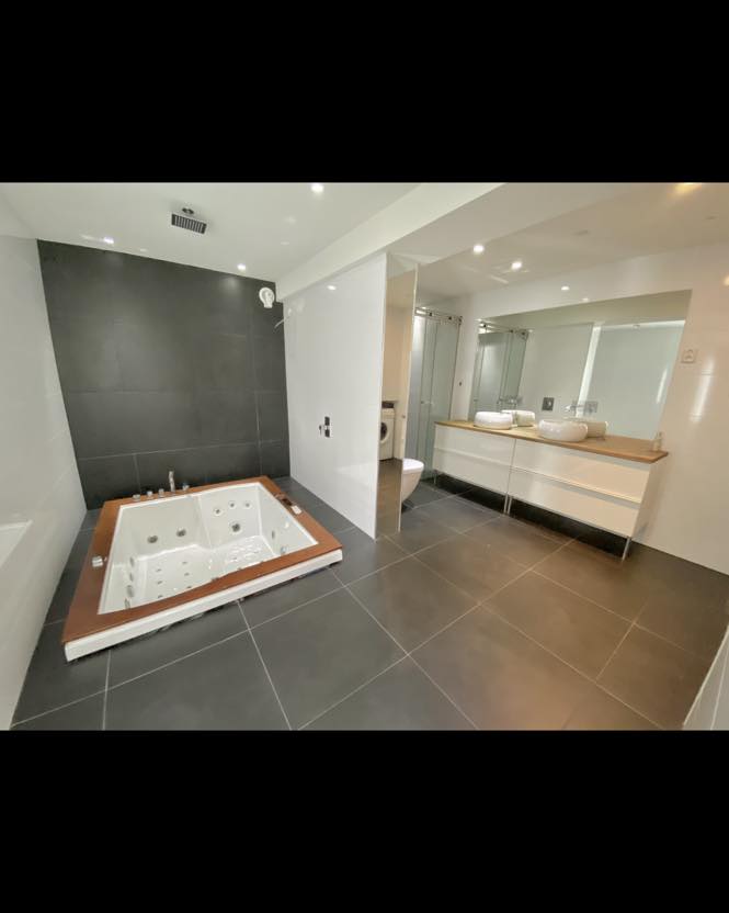 Eksklusivt oppusset bad med nedfelt boblebad, dobbel servant, dusj og vaskemaskin – moderne og funksjonell løsning levert av Mjøsbygg
