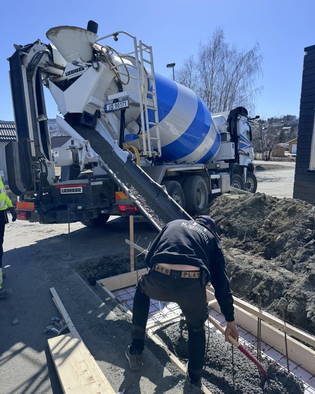 Støping av såle og murvegg på Gjøvik – sementbil i bakgrunnen og håndverker fra Mjøsbygg som fyller på støpemasse