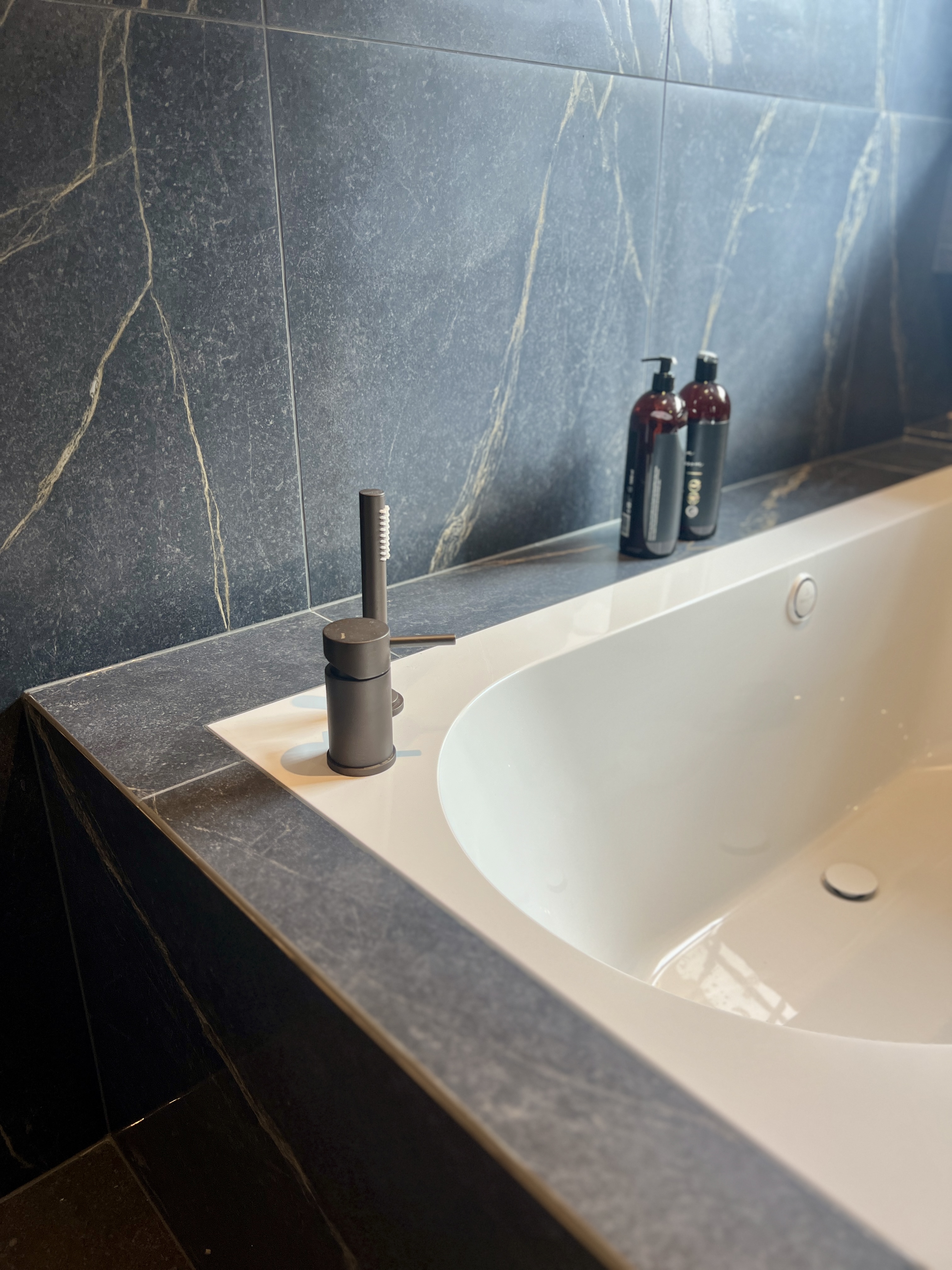 Renovering av bad i Gjøvik – store mørke fliser og badekar i samme fliser gir et moderne og elegant uttrykk, arbeid utført av Mjøsbygg